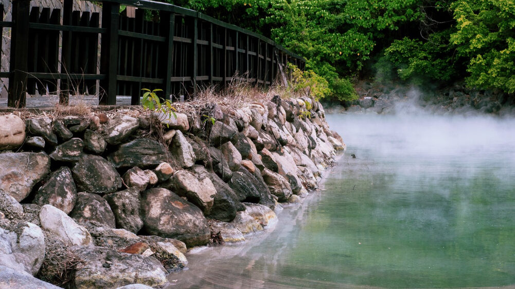 Suasana tenang pemandian air panas alami yang dikelilingi pepohonan hijau di Kinosaki Onsen, momen relaksasi eksklusif untuk Private Trip Jepang Anda
