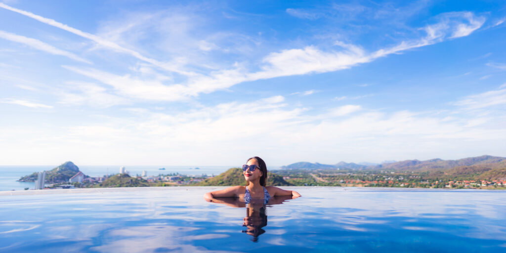 Wanita menikmati kolam renang infinity dengan pemandangan pegunungan sebagai bagian dari layanan perjalanan privat.