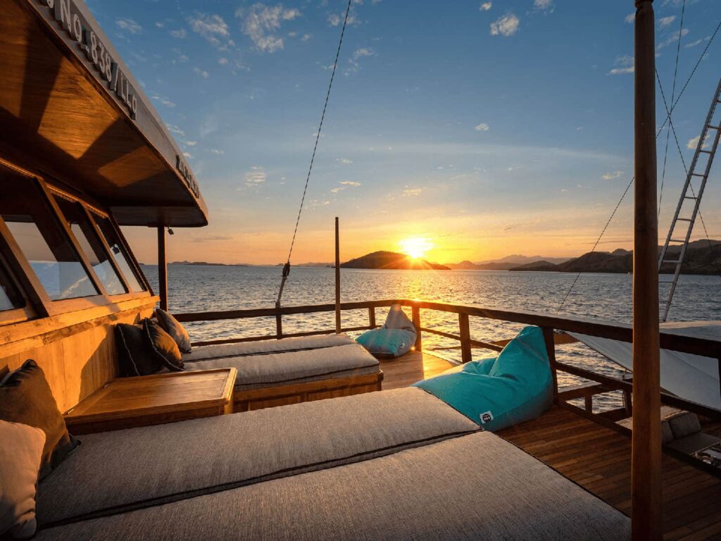 A premium liveaboard boat sailing at sunset, offering the ultimate luxury Labuan Bajo tour experience.