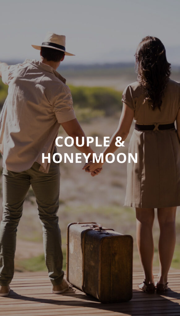 Pasangan membawa koper di tepi pantai untuk perjalanan romantis yang inklusif dan privat.