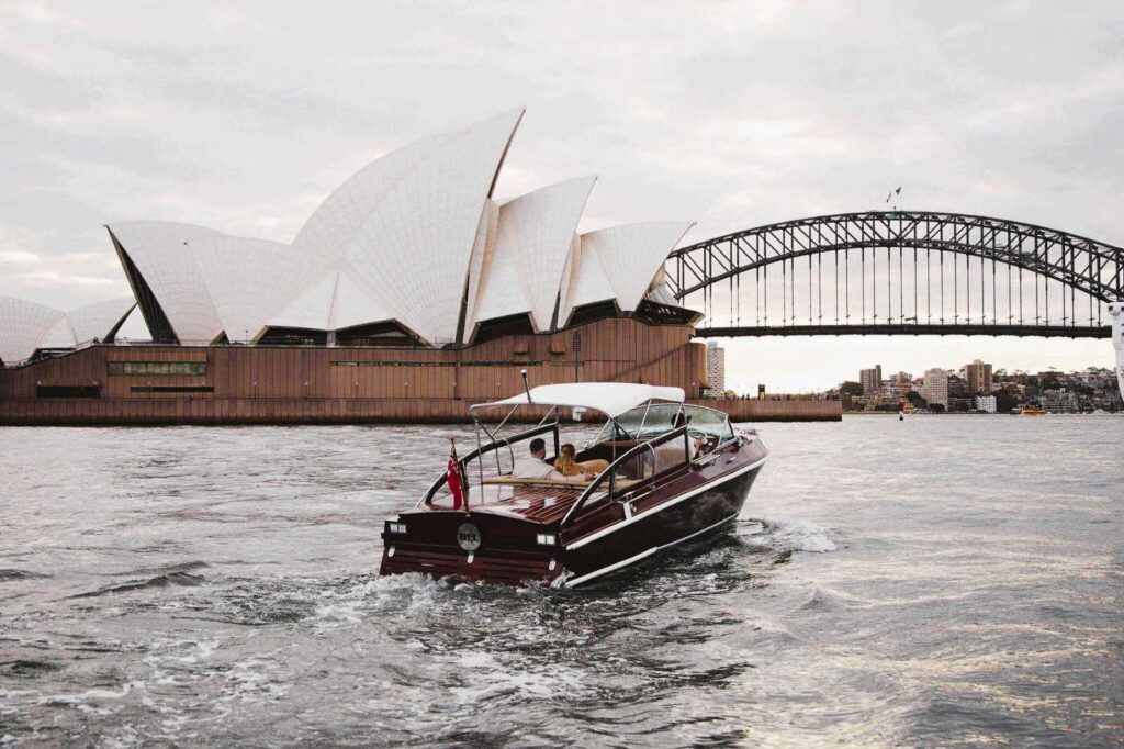 Pasangan menikmati perjalanan perahu pribadi dengan pemandangan ikonik Sydney Opera House dan Harbour Bridge, bagian dari triplelines private trip luxury Australia.