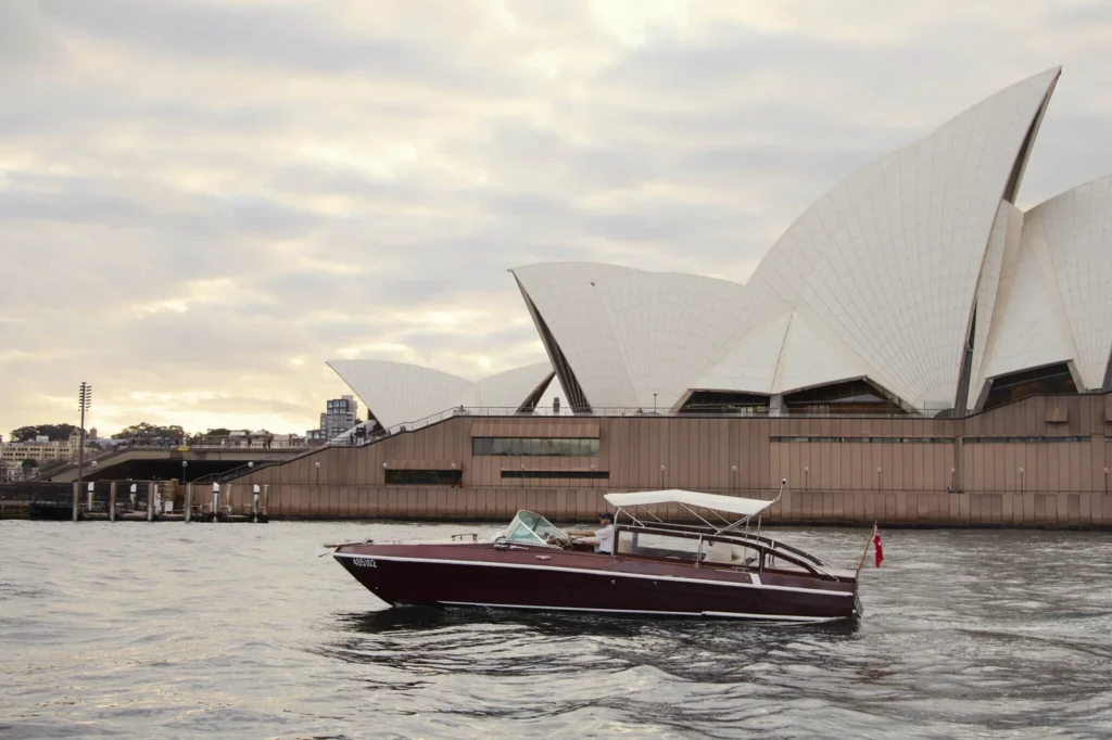 Kapal pesiar klasik mewah melintasi perairan Sydney dengan latar belakang Sydney Opera House, layanan eksklusif dari triplelines private trip luxury australia.