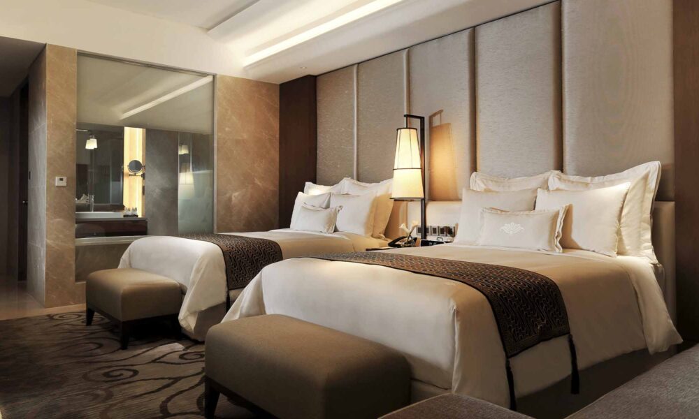 A luxurious deluxe twin room at Hotel Tentrem featuring elegant Javanese accents and warm lighting, perfect for those seeking the peaceful echoes of a Java journey.