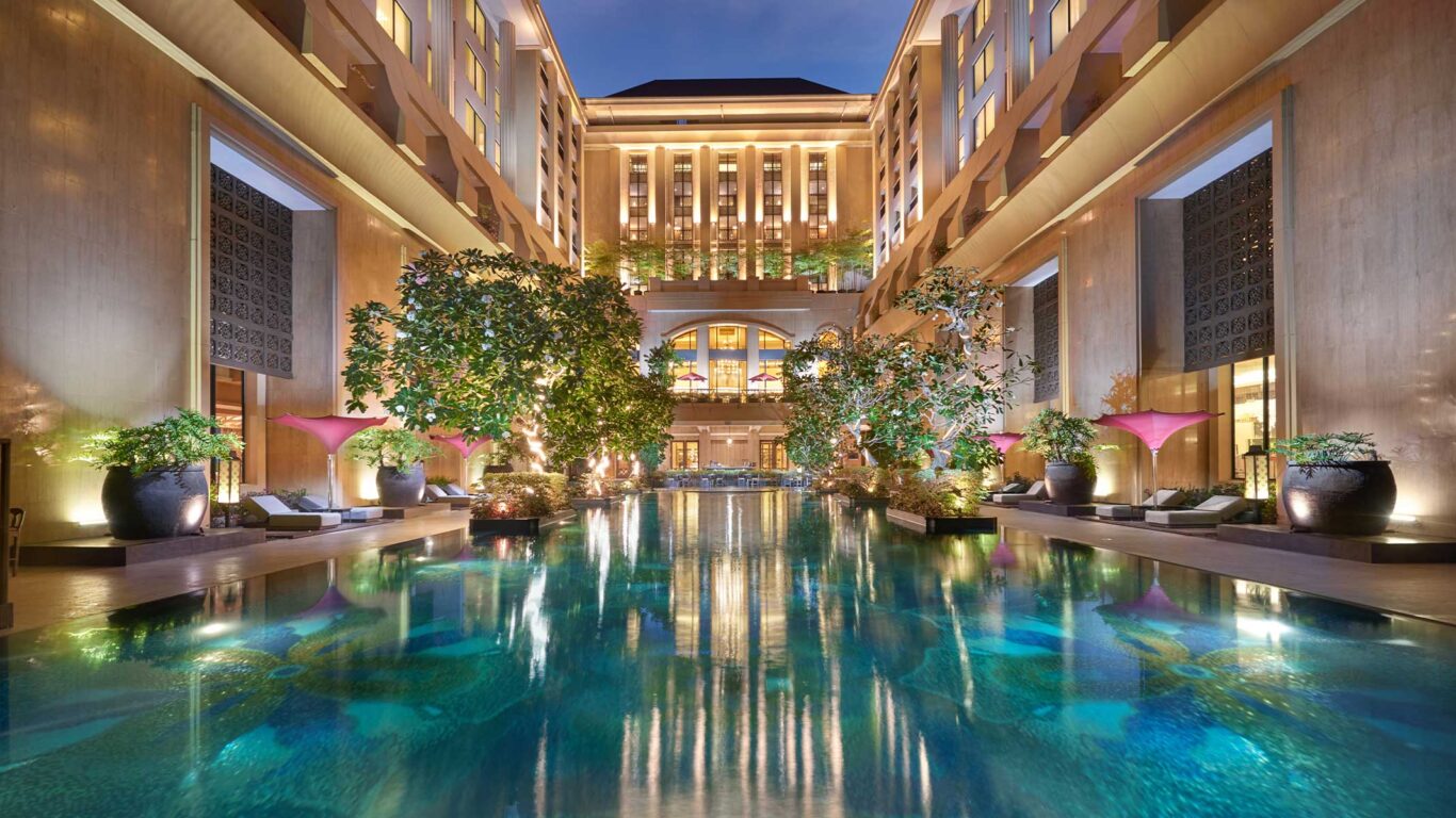 The stunning outdoor swimming pool at Hotel Tentrem, surrounded by grand architecture that captures the serene echoes of a Java journey at sunset.