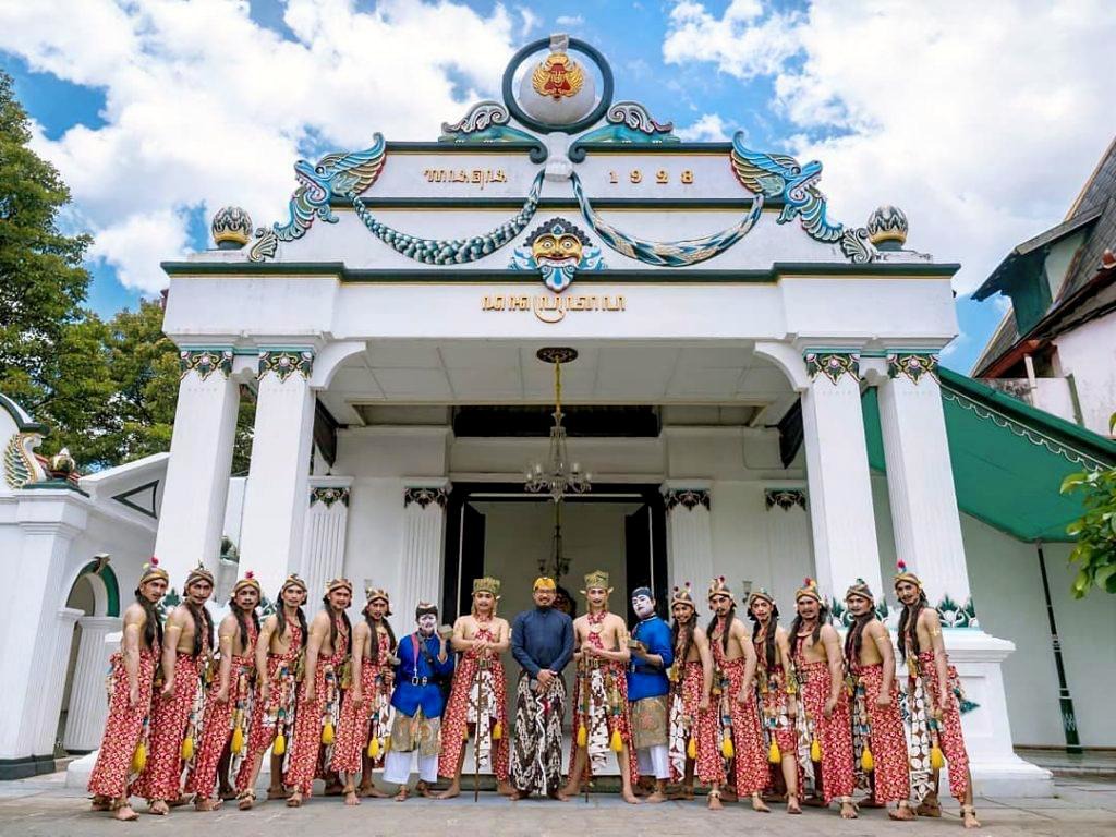 A group of traditional Javanese palace guards and performers posing in front of a white ceremonial building at the Keraton Yogyakarta.